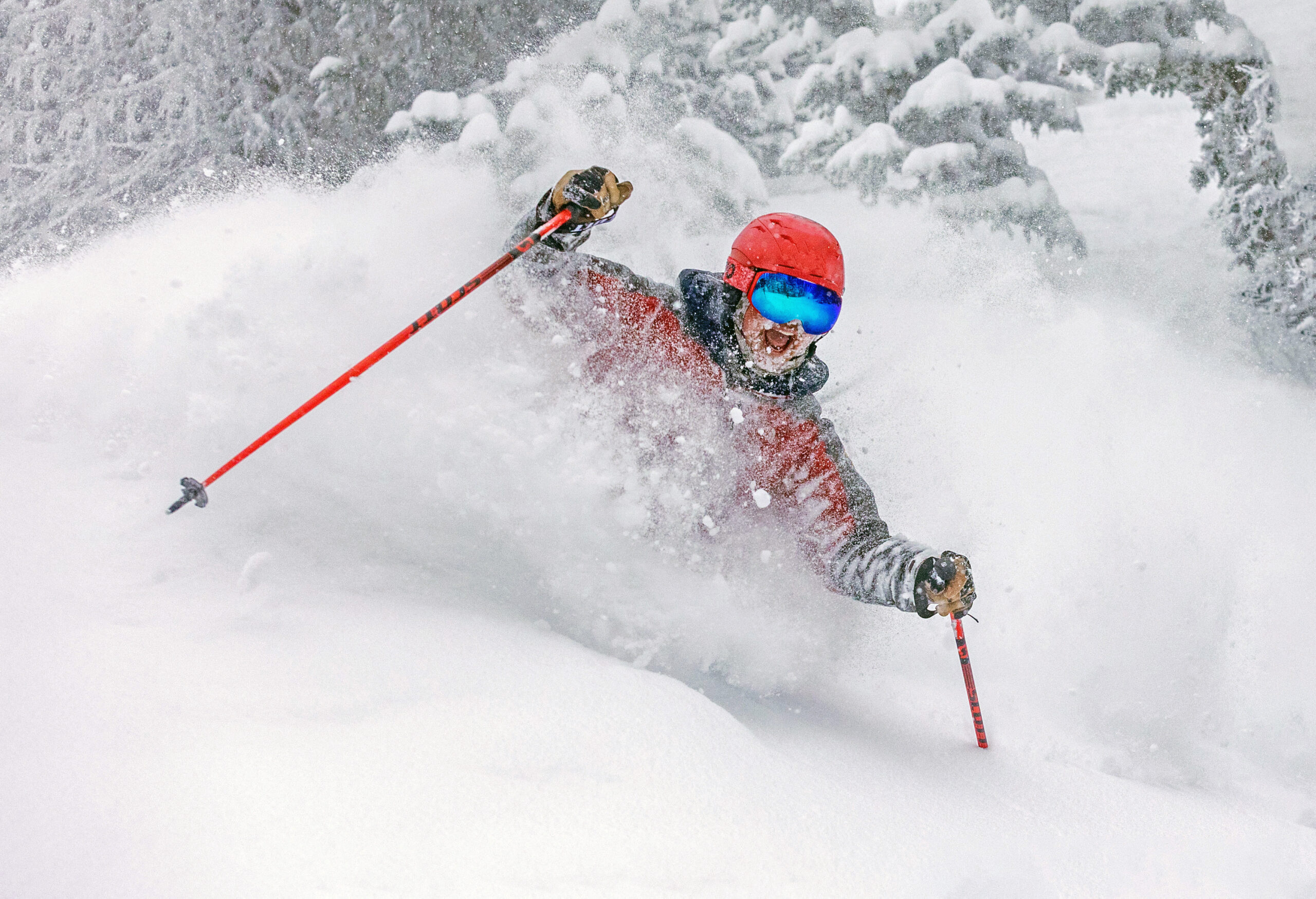 Skier at Mission Ridge in red jacket and helmet smiling during a deep powder turn