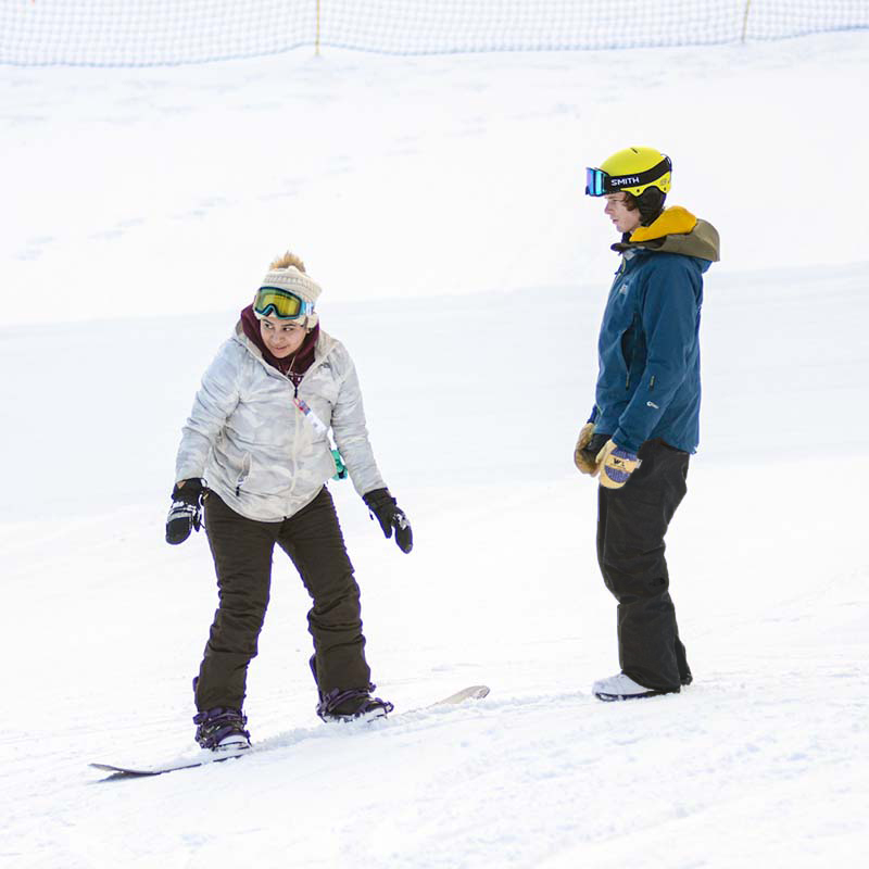 Instructor watching snowboard student making turn