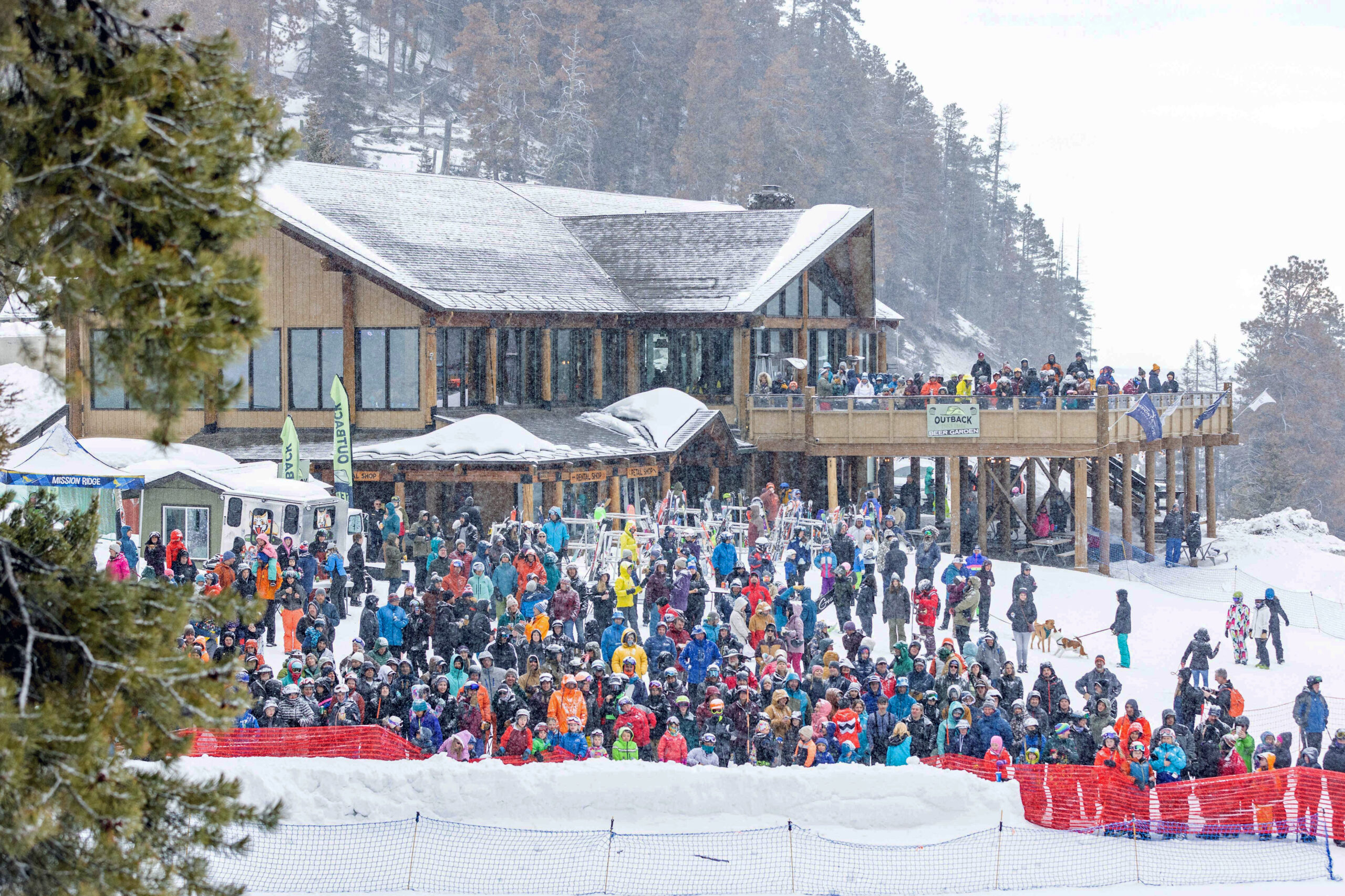 Large group of spectators in the Mission Ridge base area standing in front of the lodge during a snowstorm