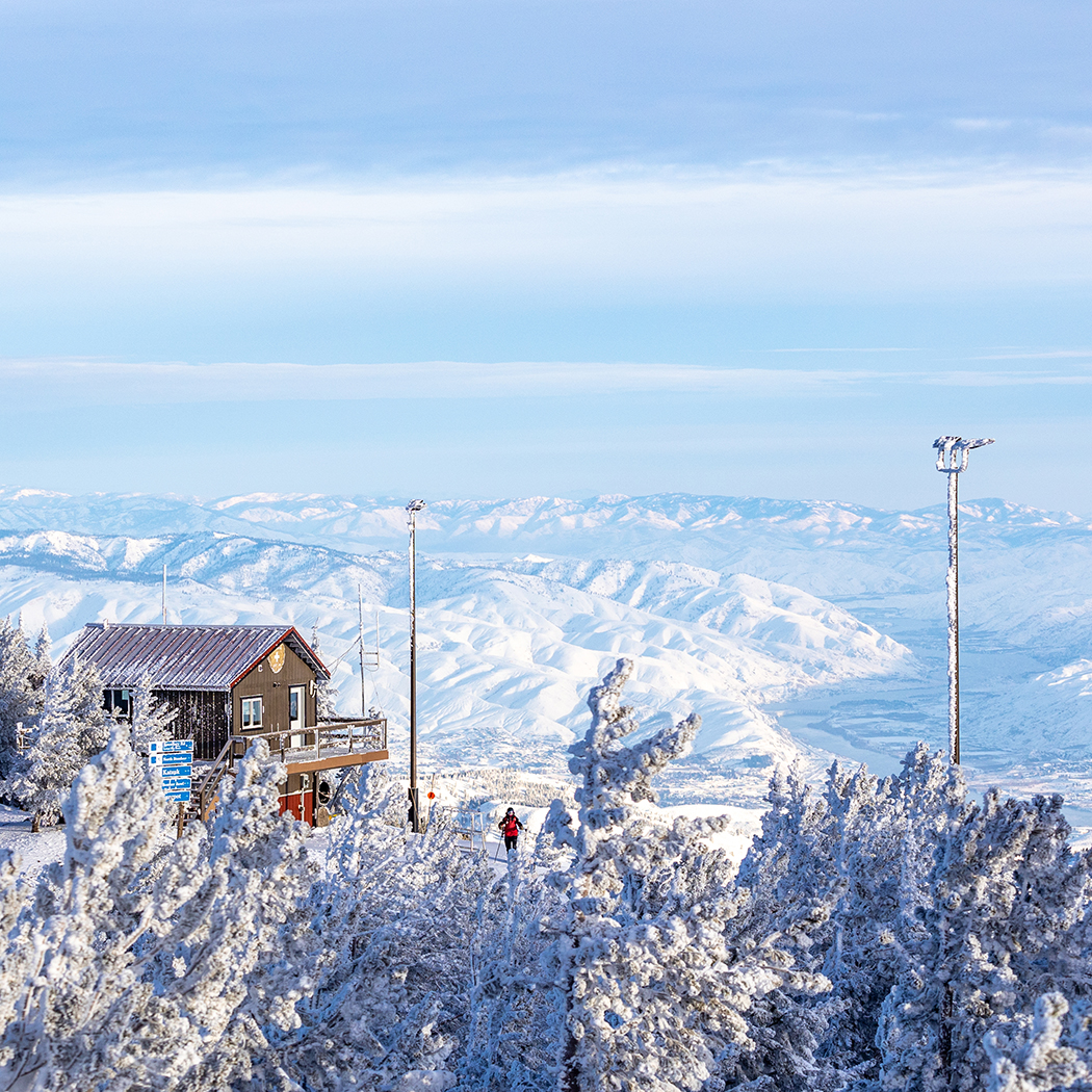 Summit Patrol Shack surrounded by snow covered trees and valley view below