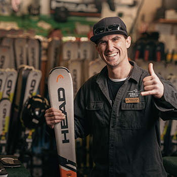 Rental Technician smiling and holding pair of skis