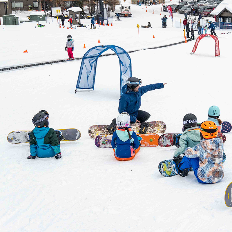 Snowboard instructor talking to a group of young snowboarders