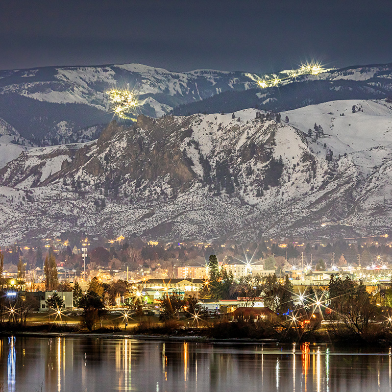 View of Mission Ridge and Wenatchee at night covered in snow from across the Columbia River.