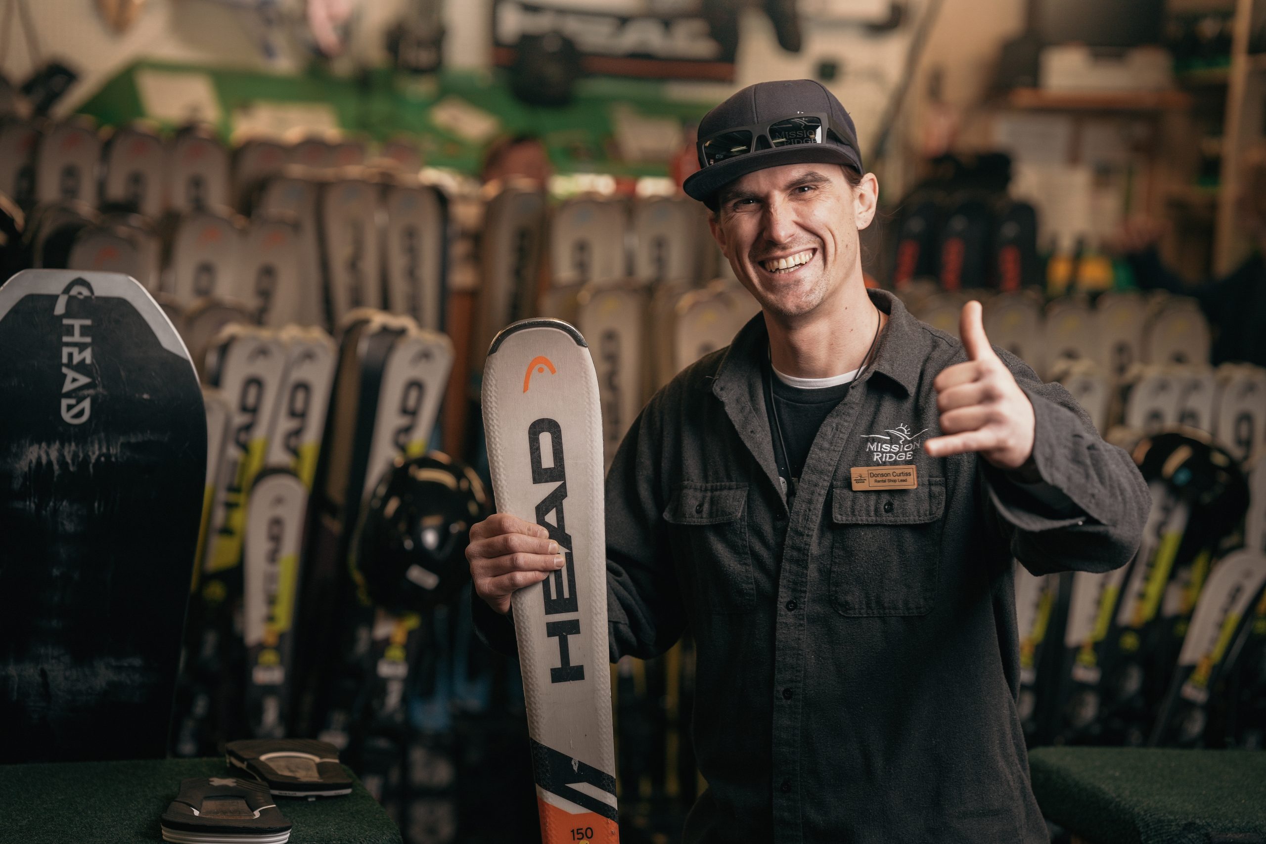 Rental Technician smiling and holding pair of skis