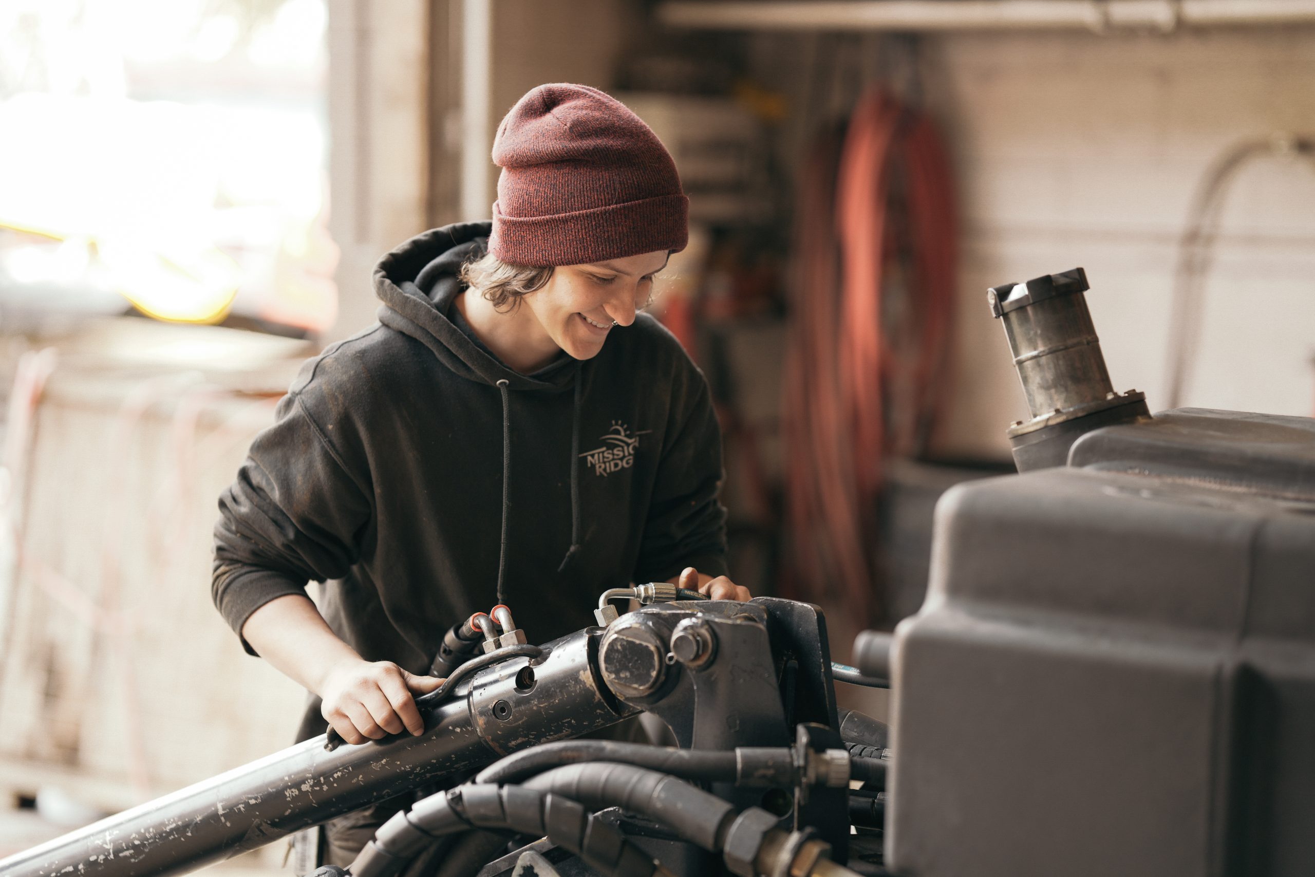 Vehicle mechanic smilign while working on a snow cat engine