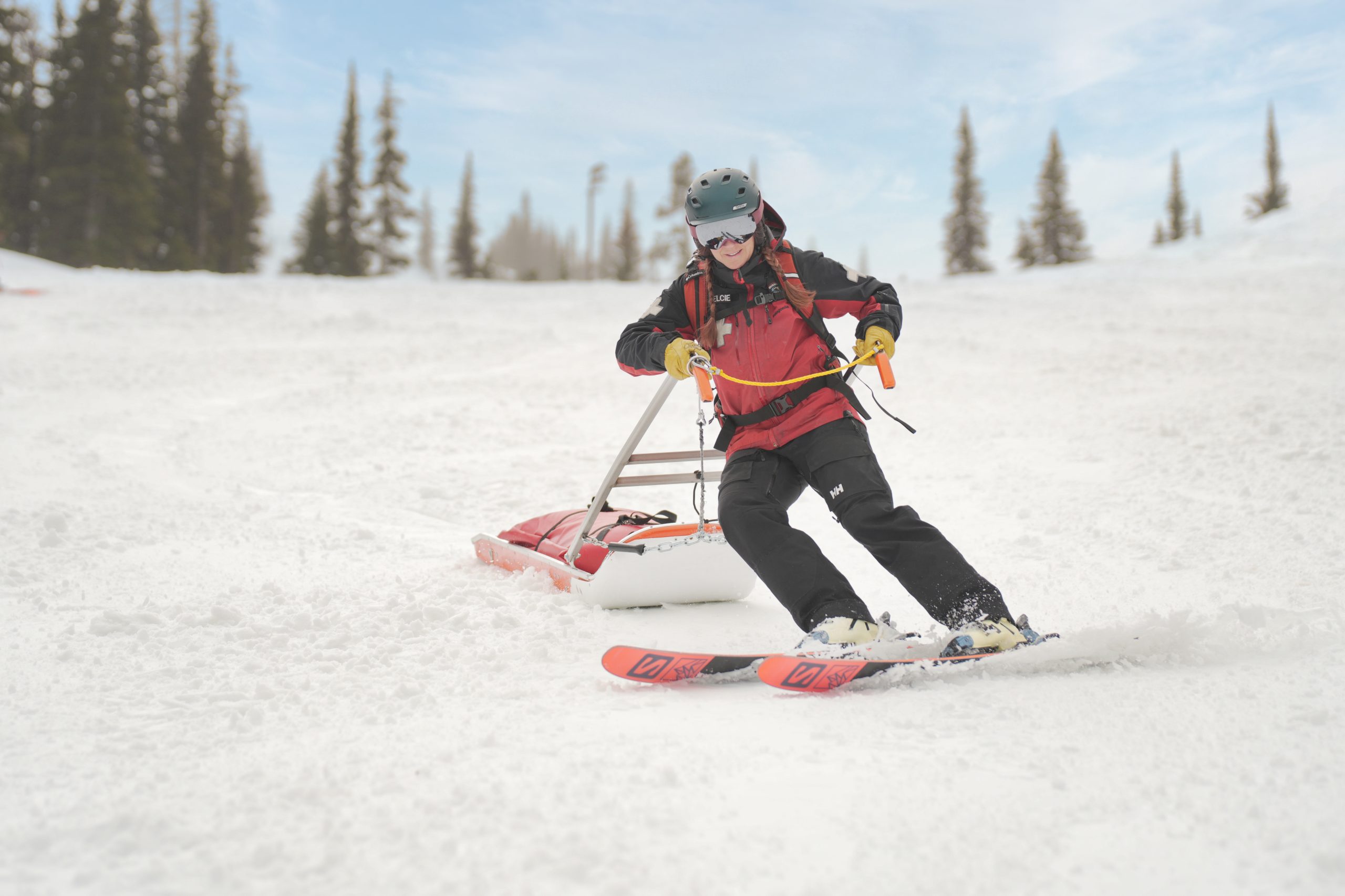 Ski patroller turning on snow with empty toboggan