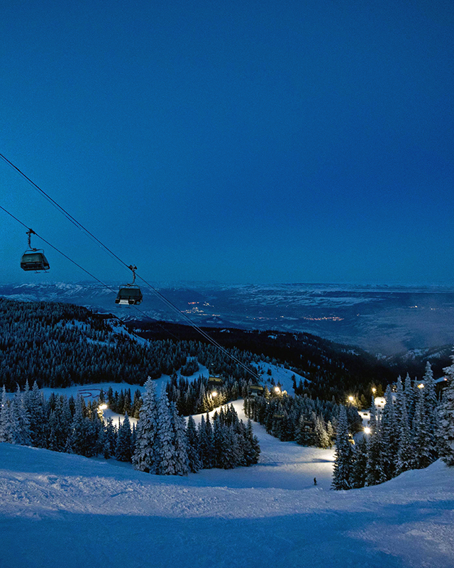 View of chairlift, night lights, and valley view at twilight.