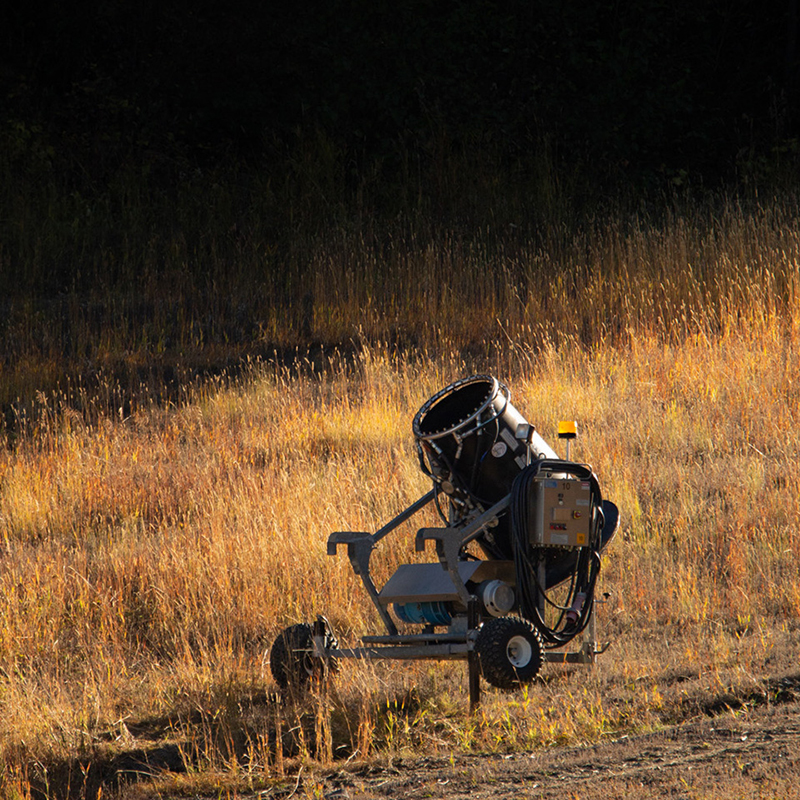 Black snow gun surrounded by golden grass in the fall