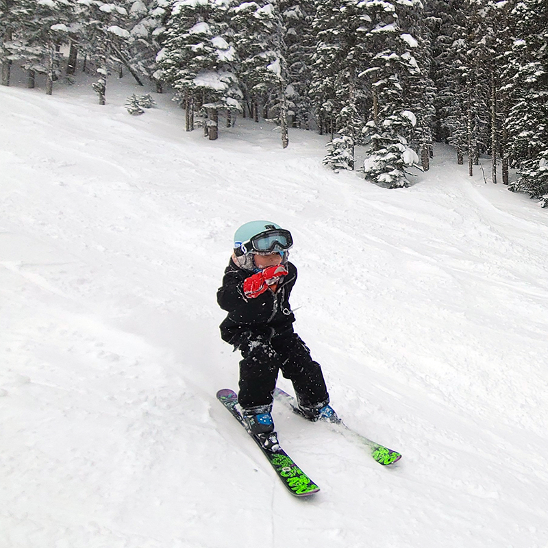 Young skier with no poles making turn on fresh snow
