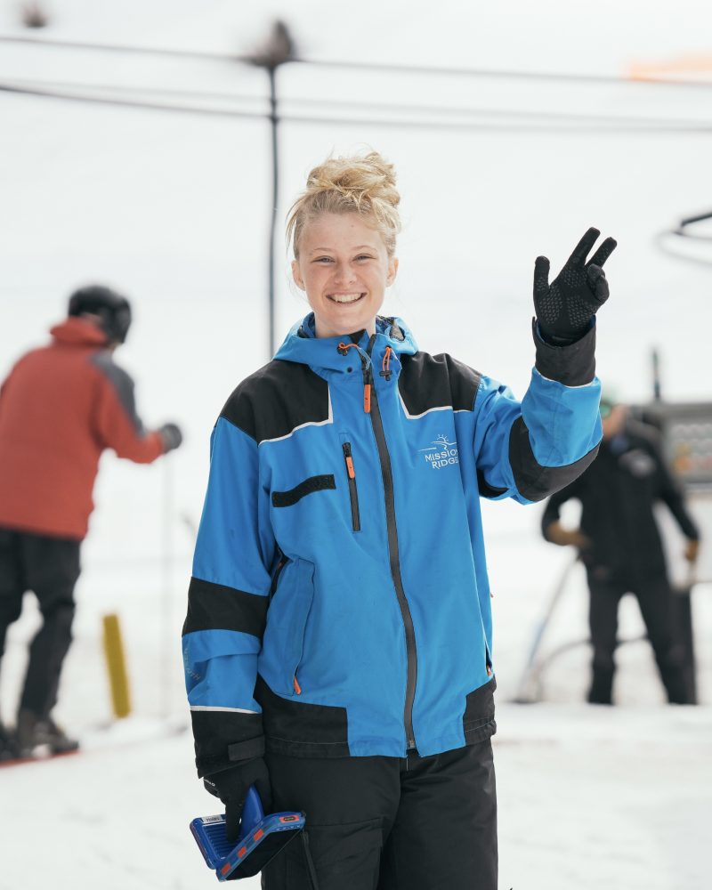 Photo of a Mission Ridge employee outside in the snow waving at the camera