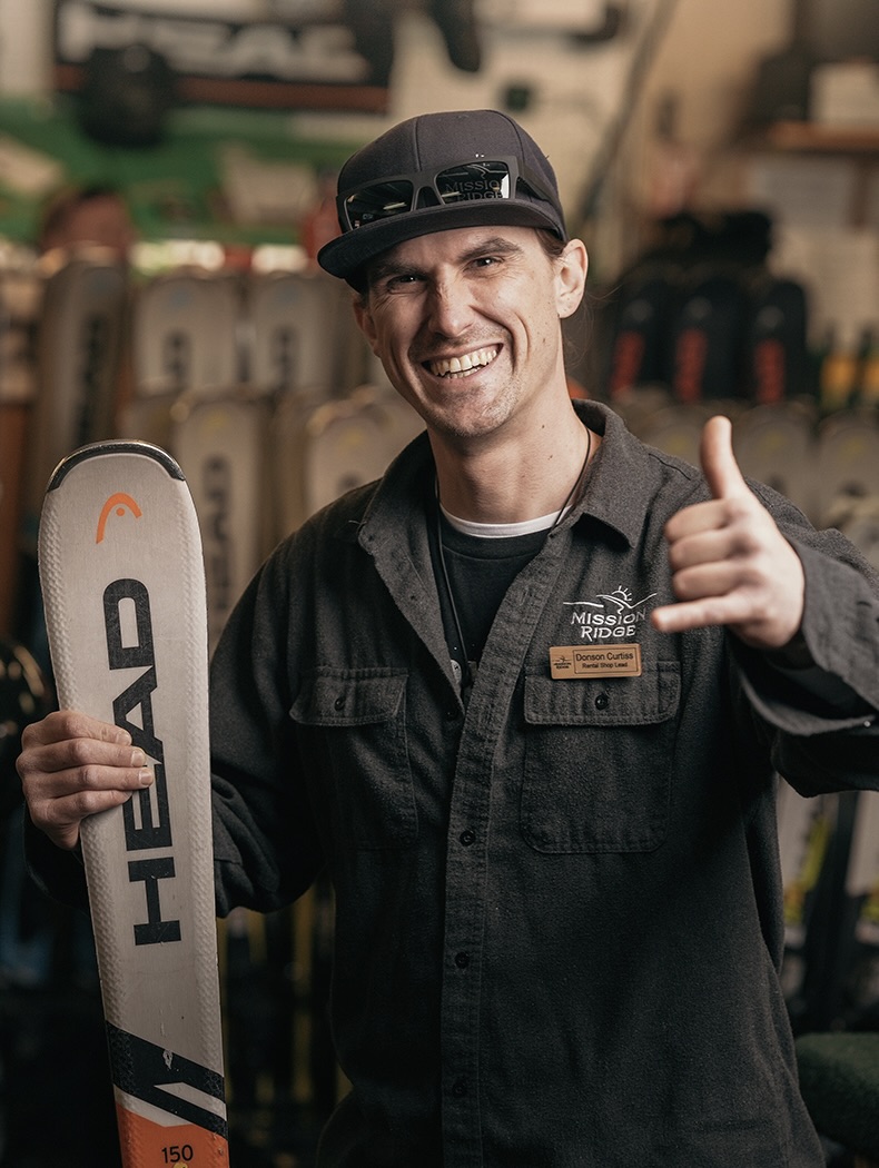Rental Technician smiling and holding pair of skis