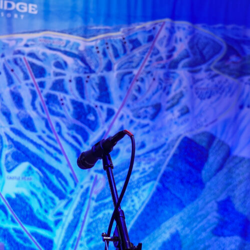 Close up of microphone with Mission Ridge trail map behind bathed in blue light