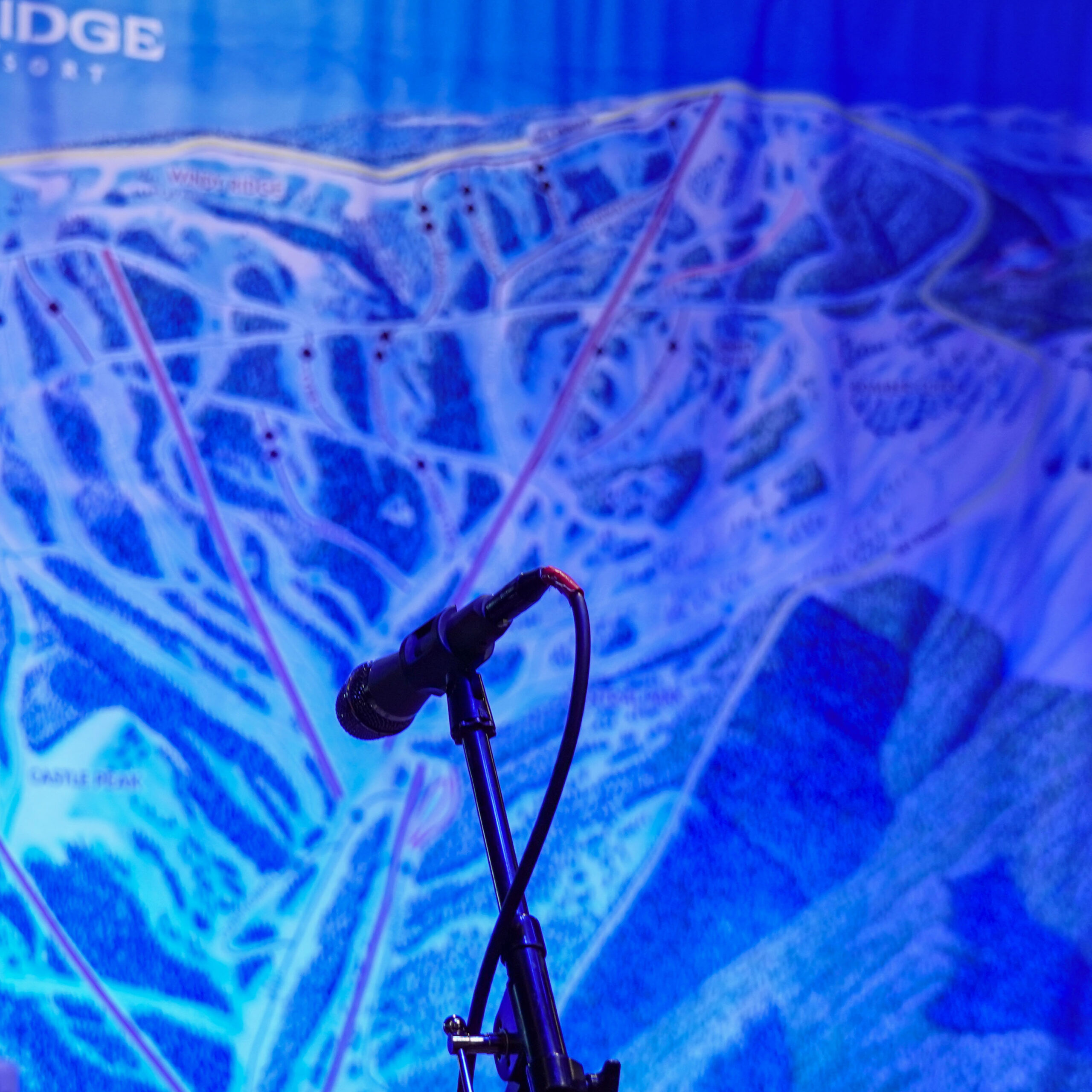 Close up of microphone with Mission Ridge trail map behind bathed in blue light