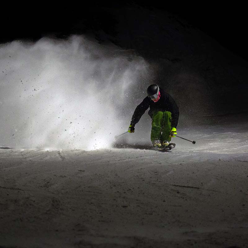 Skier slashing the snow under the lights during night skiing at Mission Ridge.