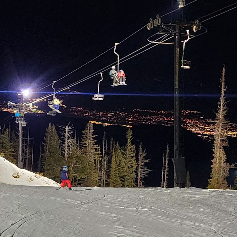 Skiers on Chair 4 at Mission RIdge with valley lights below