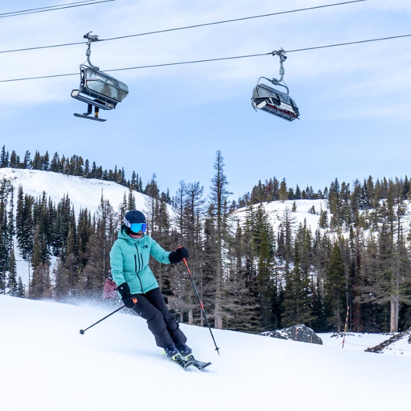 Skier on groomed run with chairlift overhead