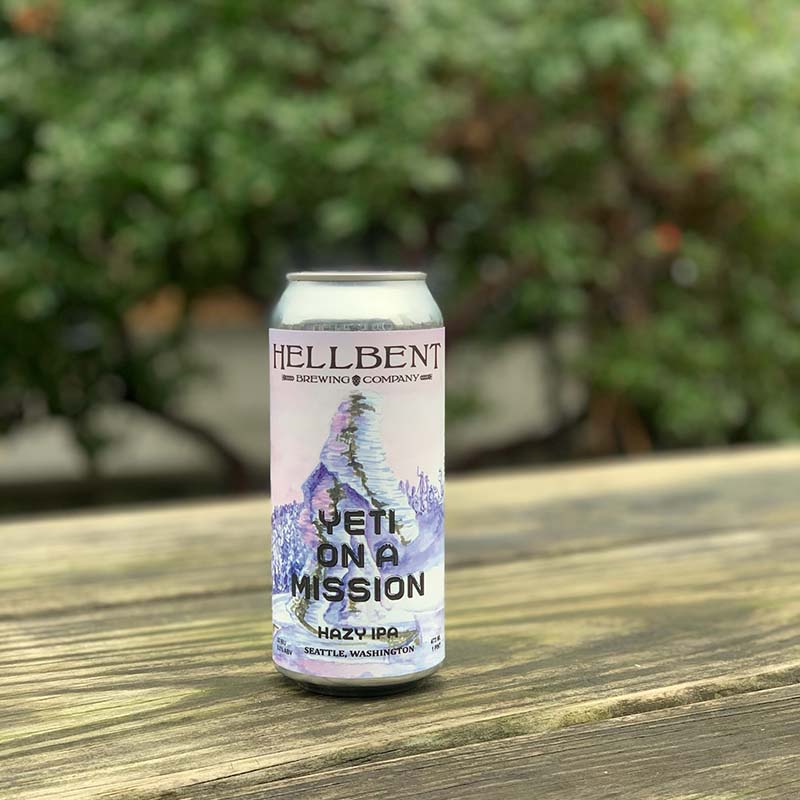 Can of "Yeti On A Mission" beer by Hellbent Brewing sitting on a wood table outside.