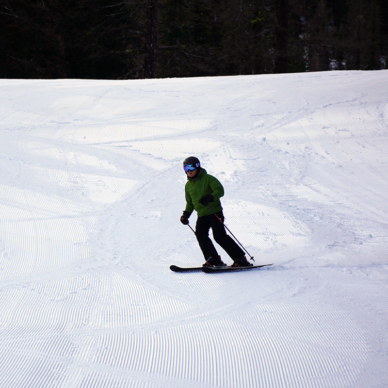 Skier in green jacket making turn on fresh corduroy on the Sitkum run at Mission Ridge