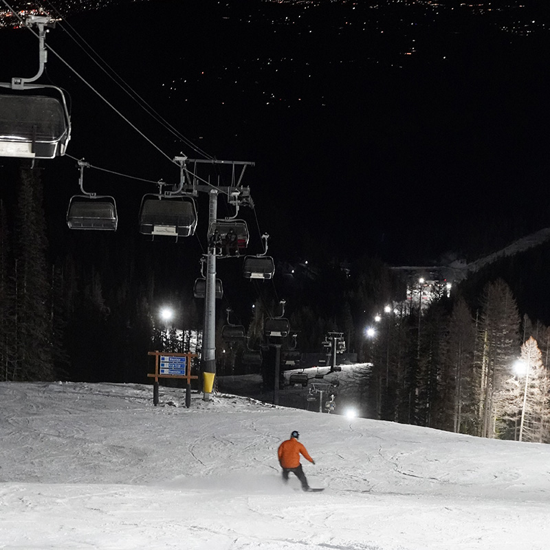 Snowboarder making turn during night skiing under the Wenatchee Express chairlift on the Tumwater run at Mission Ridge.