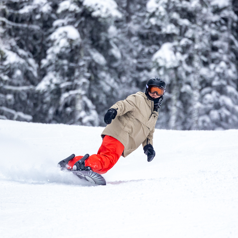 Snowboarder leaning toeside on a freshly groomed run