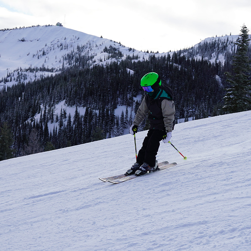 Young skier in green helmet on Bomber Bowl run at Mission Ridge