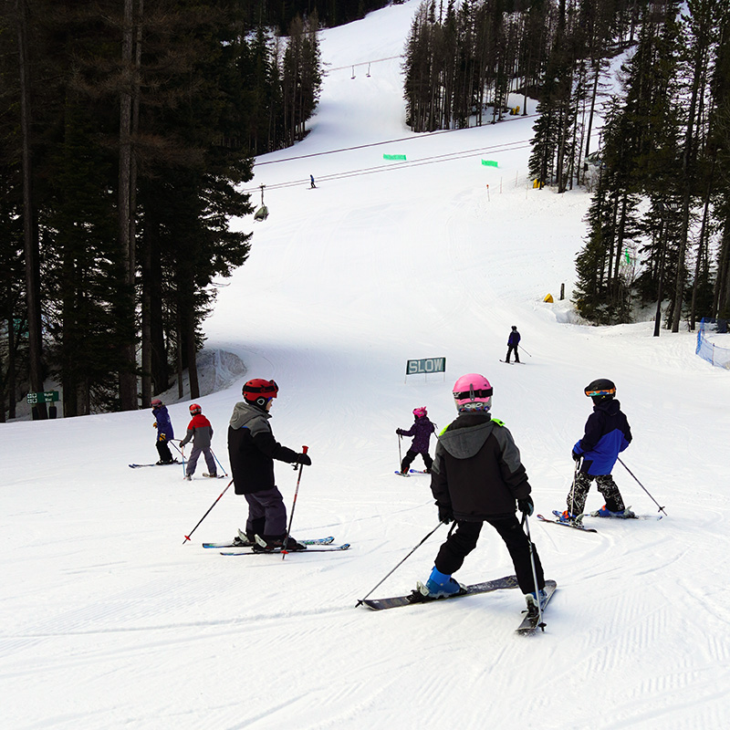 Group of multiweek ski program students making turns on Mimi run at Mission Ridge.