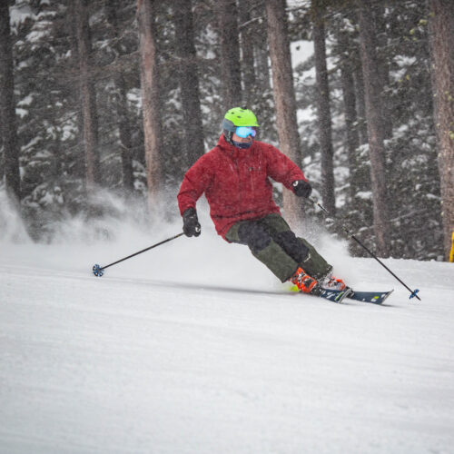 Skier in red carving the soft snow under chair 3