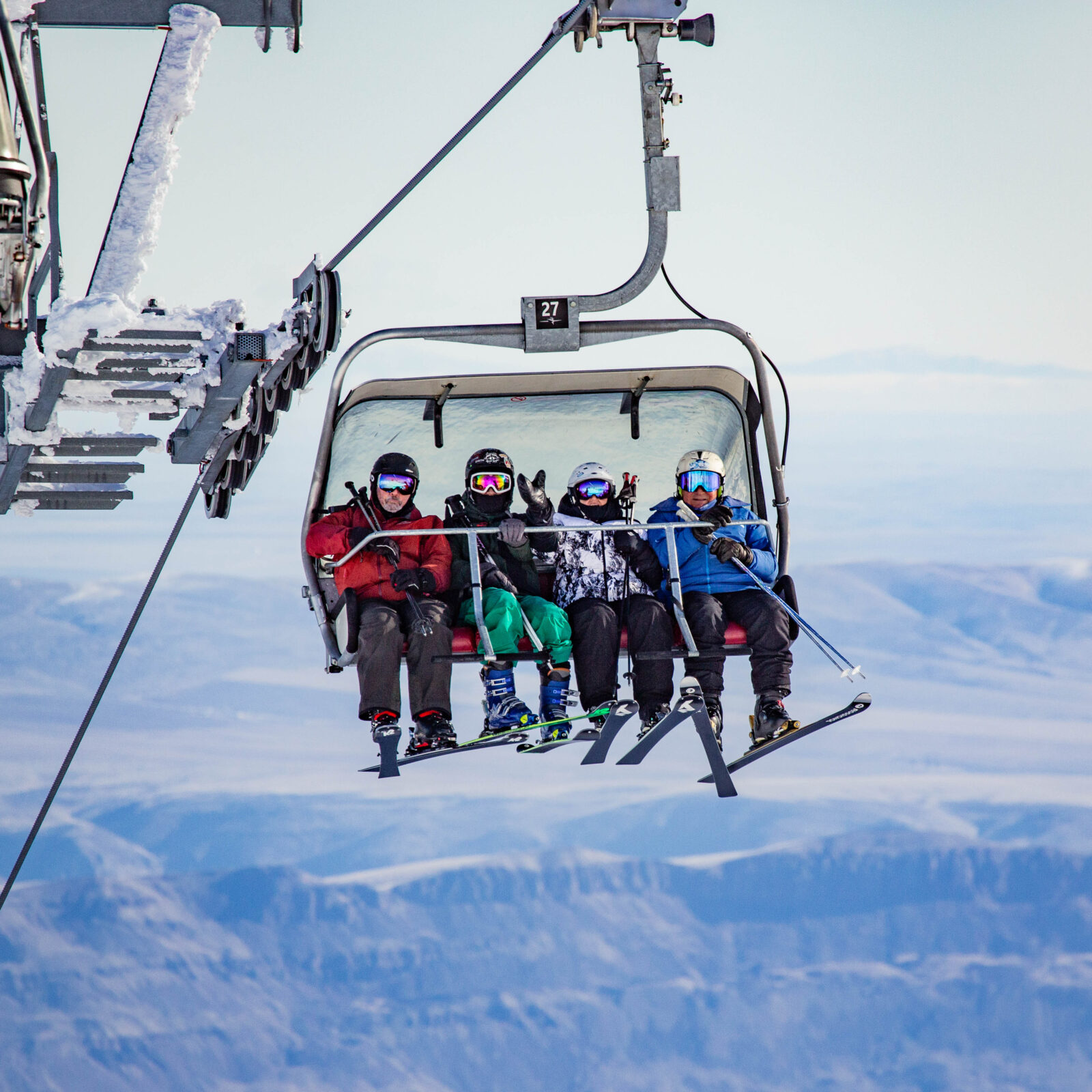 A full chair arrives at the summit against views of the valley