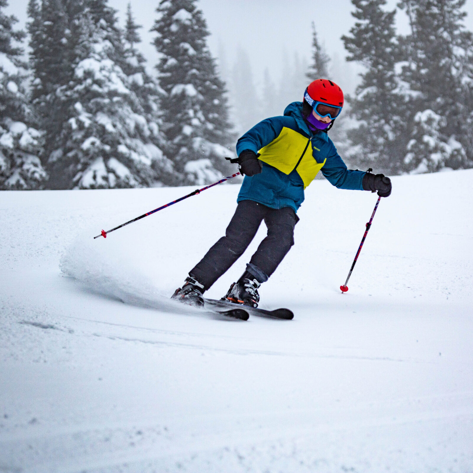 Young skier in green and yellow carving under chair 2