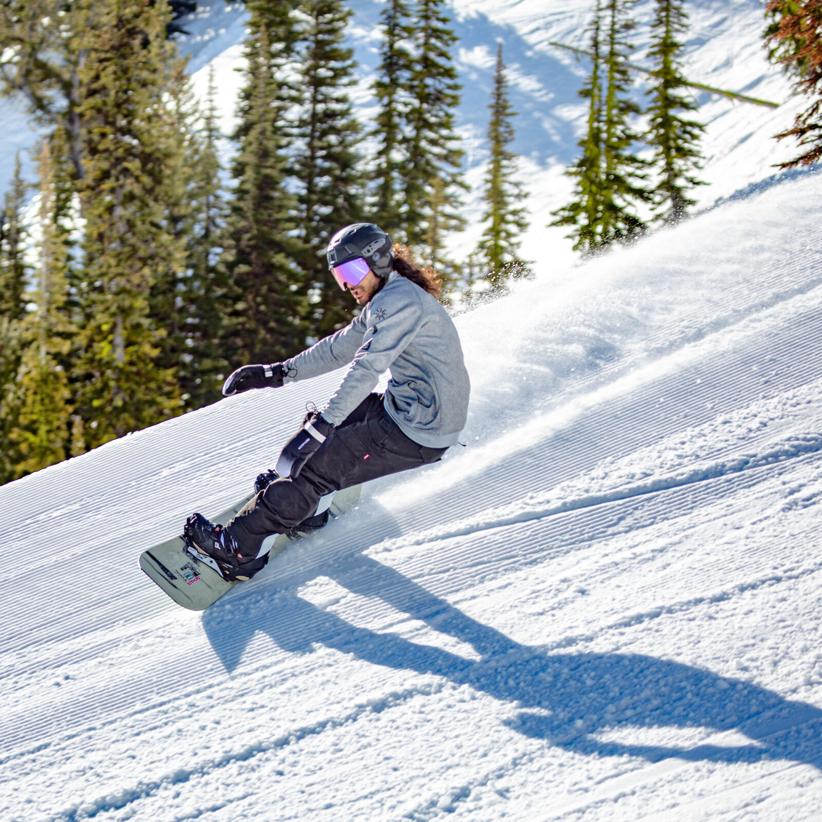 Snowboarder carving on cat track in the Bomber Bowl