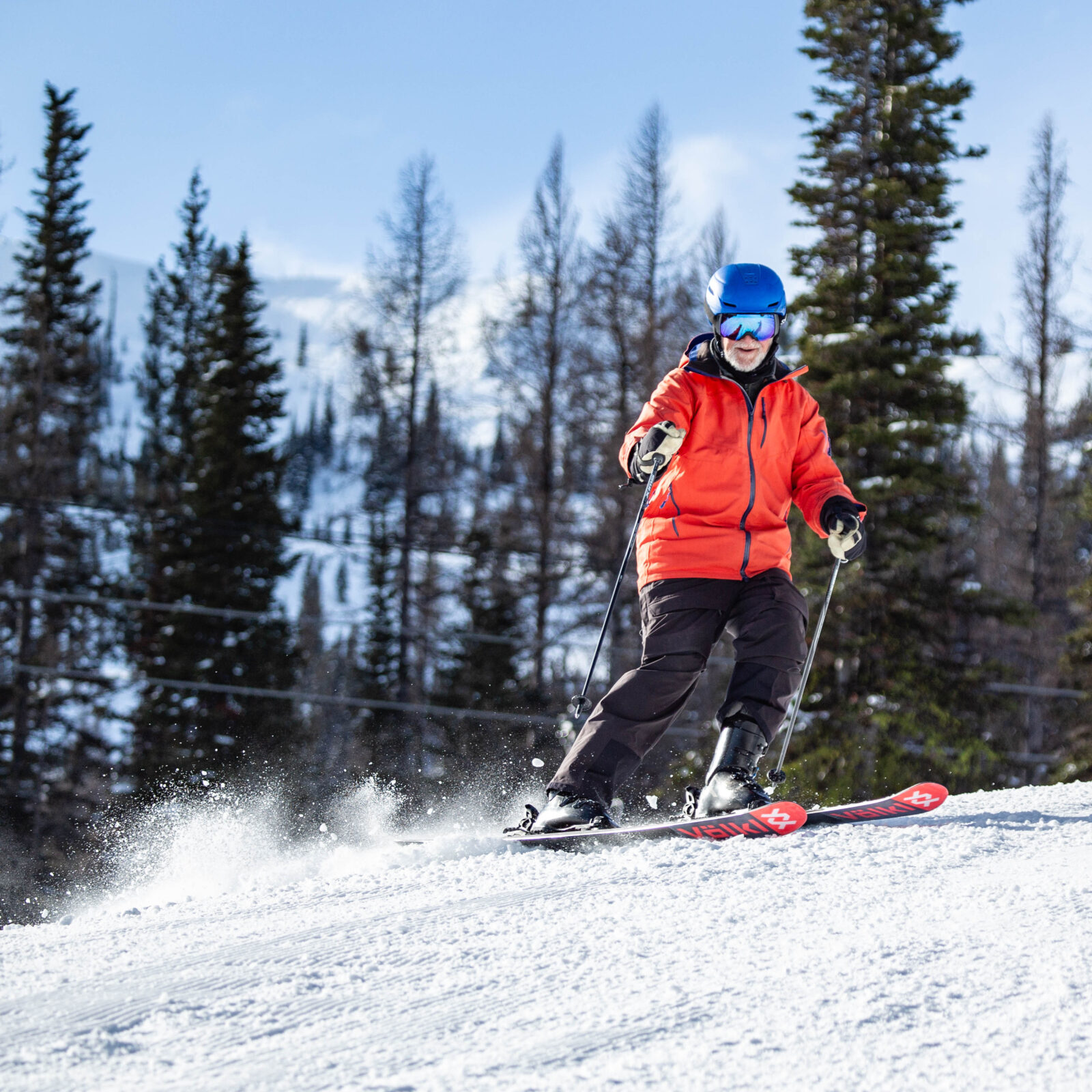 Skier in red carves below Hot Dog Hill in the sun