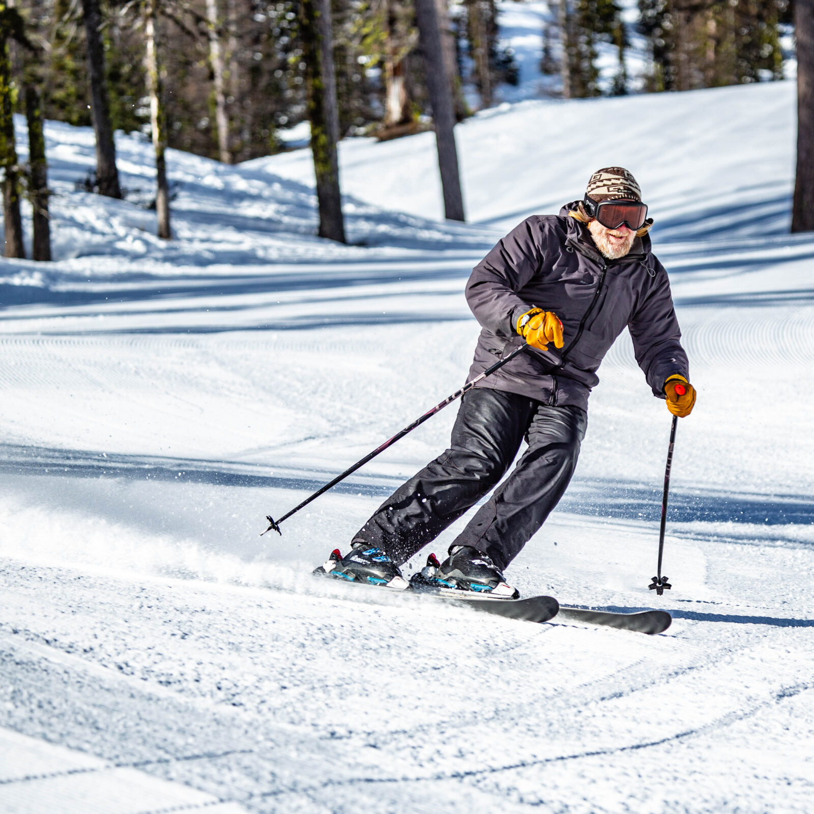 Skier in black enjoys turns in the sun while skiing in Hidden Valley