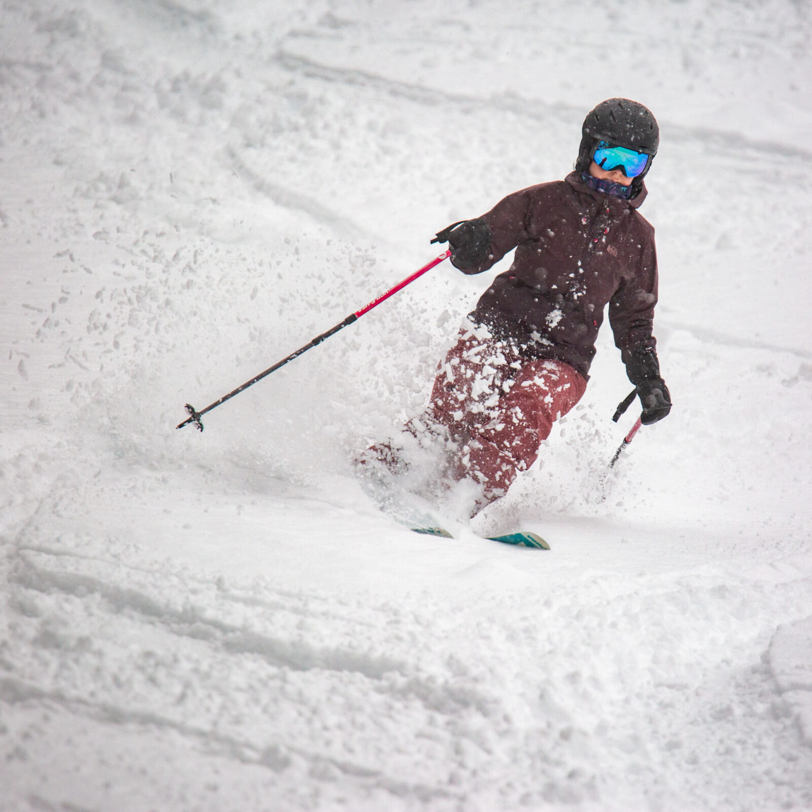 Lady skis down Kwan which is off of Chair 3 at Mission Ridge. She is skiing through powder snow which is spraying up to the side of her.