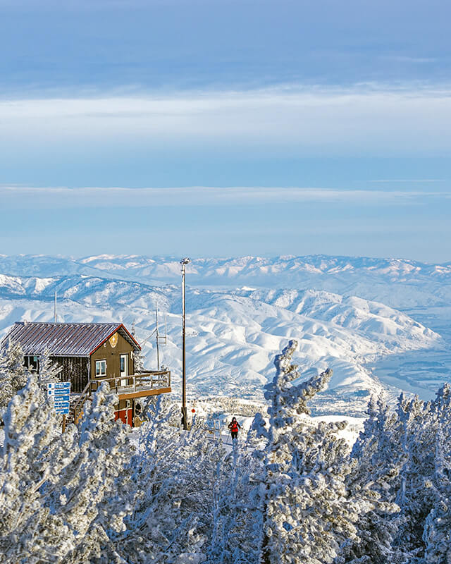 Summit Patrol Shack with patroller standing outside and valley view below