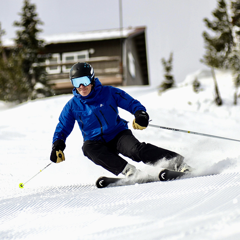 Close up of skier in blue jacket smiling while making aggressive turn on fresh corduroy at Mission Ridge.