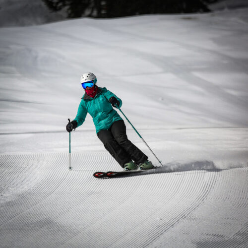Skier in green carving under chair 2