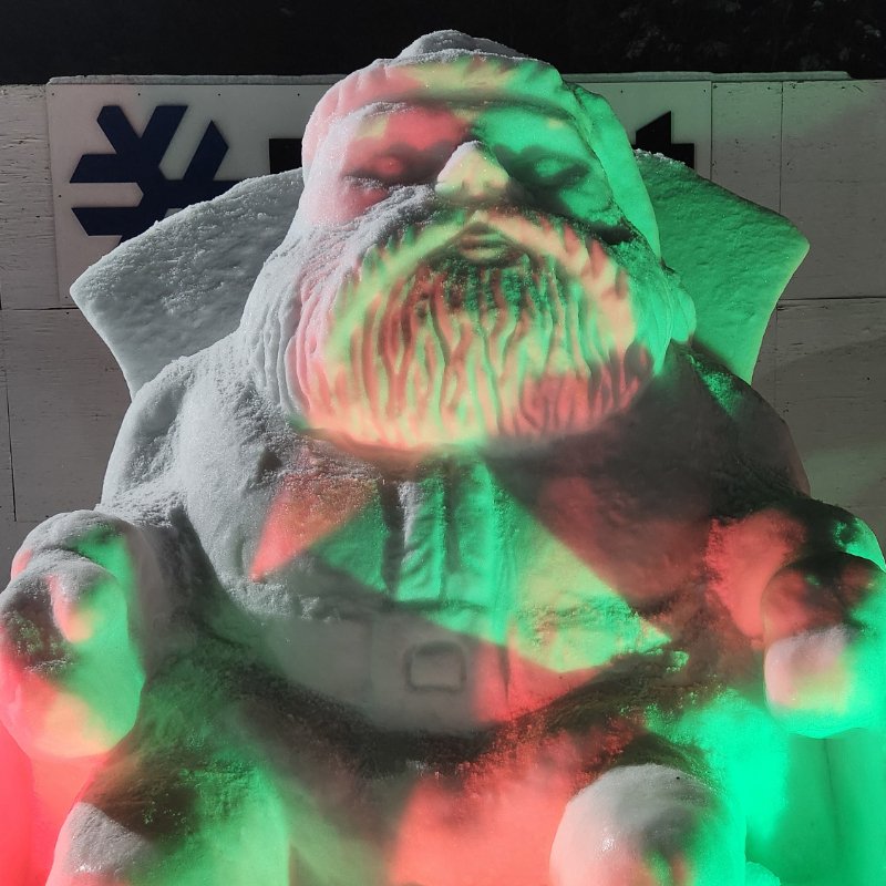 Snow sculpted Santa with red and green lights shining on it at Mission Ridge.