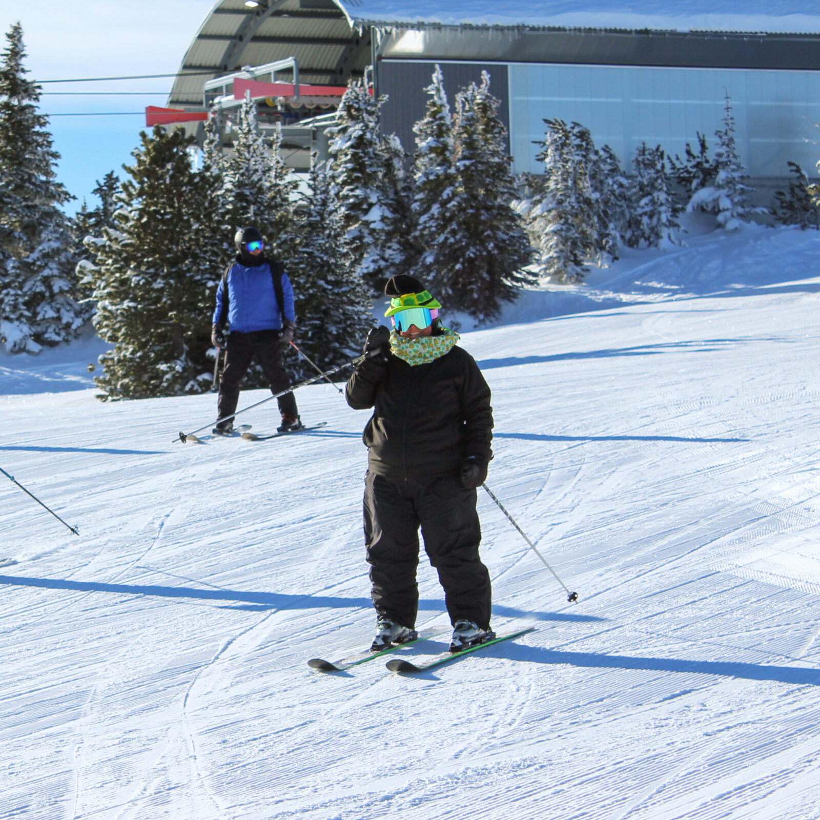 A festive skier, decked in st patrick's day gear, waves at the camera as she rides past the lift terminal