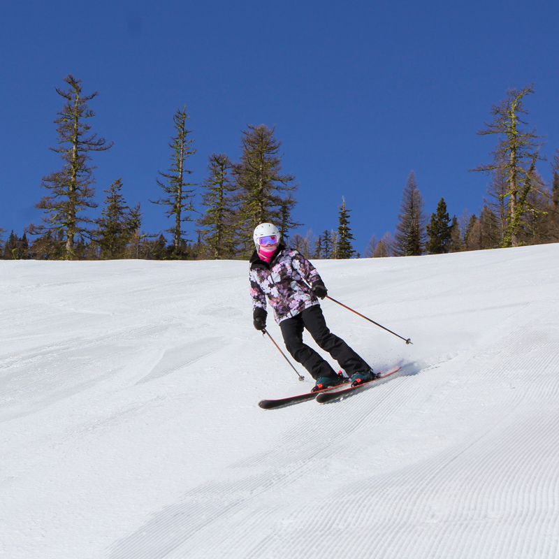 a woman skis a groomer on a sunny day
