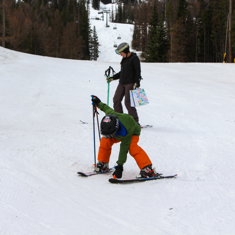 a child stoops to collect an easter egg on a ski slope