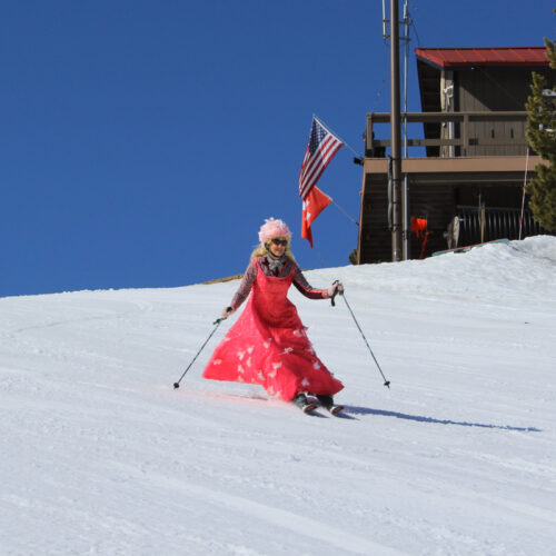 a woman in a pink dress skis past a building