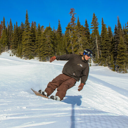 oh brother this guy Reeks! a male snowboarder in brown rides a slalom course