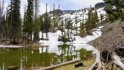 View of Lake Marion, a small lake with forest, snow, and a mountain in the backdrop. 