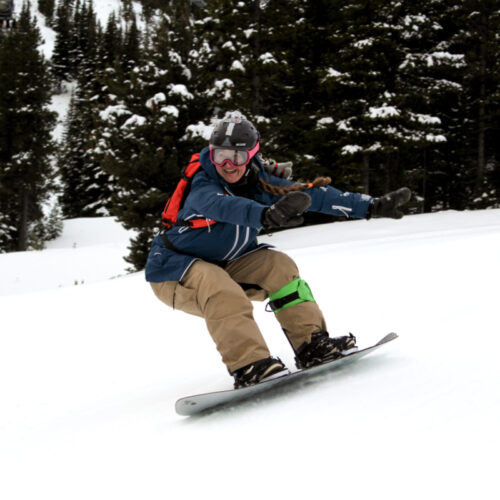 an enthusiastic woman rides a snowboard