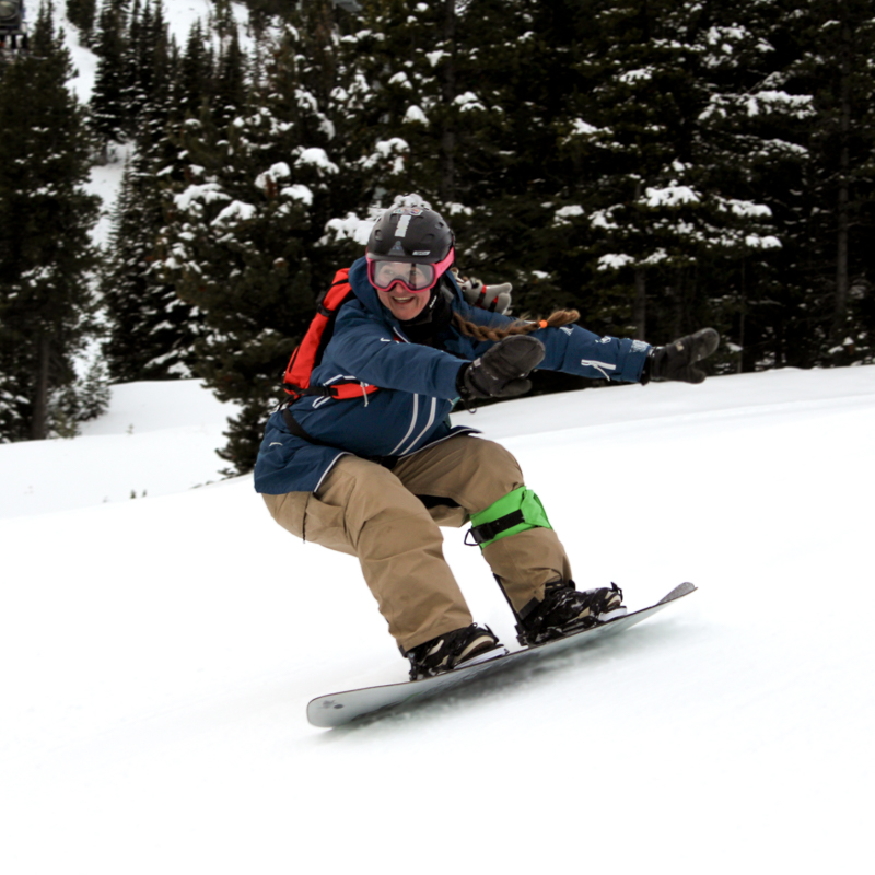 an enthusiastic woman rides a snowboard