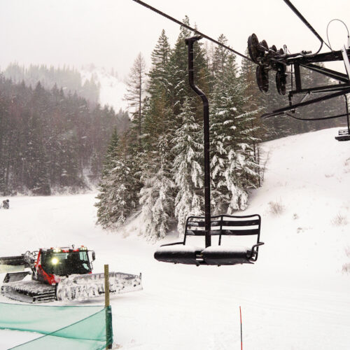 A snowy scene at the Mission Ridge base area including a chairlift and snowcat
