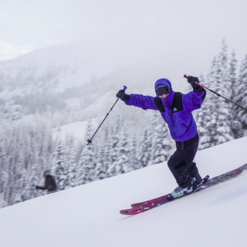 A skier smiles and waves while descending the Sunspot Trail at Mission Ridge.