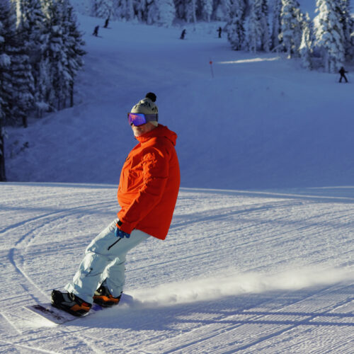 A snowboarder descends the Katsuk trail at Mission Ridge on a sunny day.