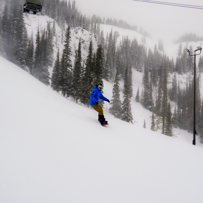 a snowboarder slides down a foggy slope