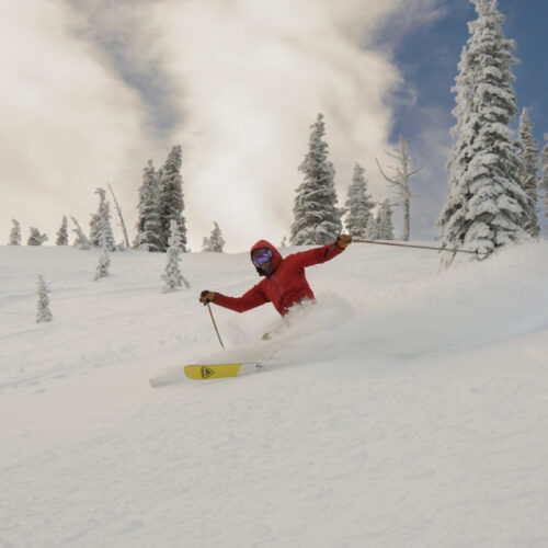 A skier slashes up some powder on a partly cloudy day at Mission Ridge.